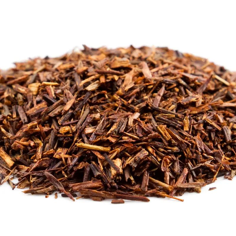 A pile of dried, cut rooibos leaf, reddish-brown, on a white background