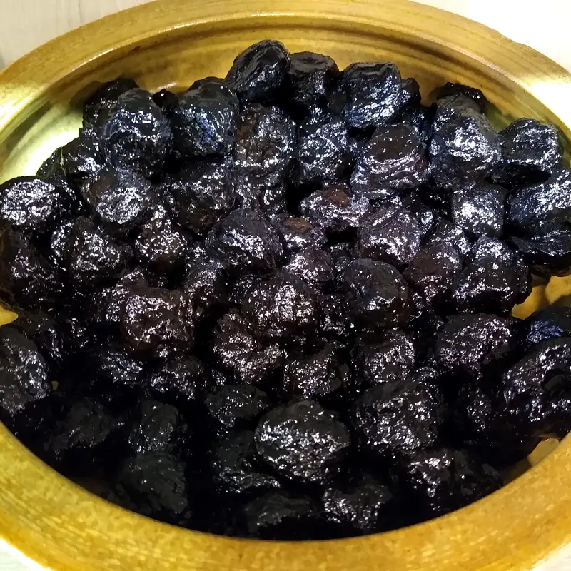 A bowl of glossy black smoked dried plums (wu mei)
