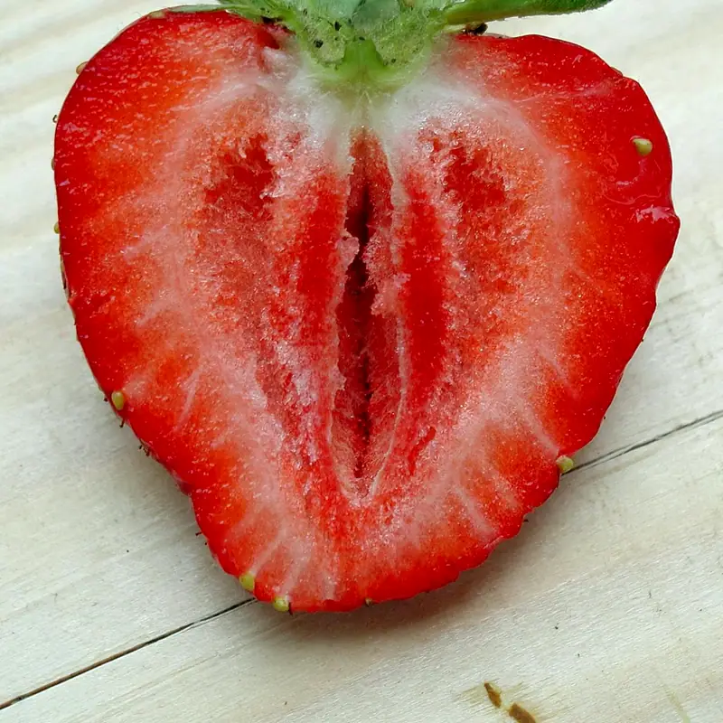 A ripe strawberry sliced in half, showing its red flesh and seeds