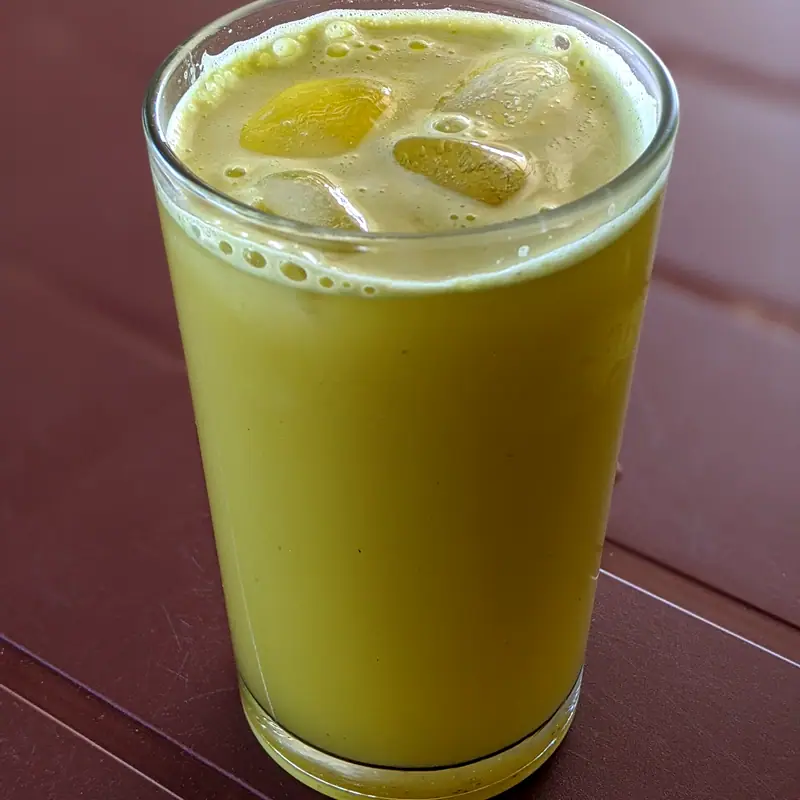 A glass of pale greenish-yellow sugarcane juice