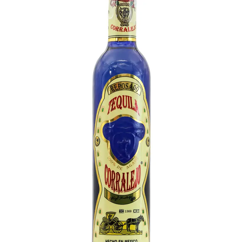 A bottle of Corralejo reposado tequila with a blue glass neck and cream label, against a plain white background