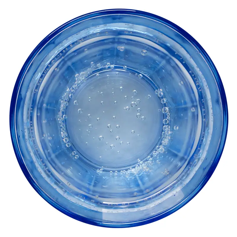 A blue glass seen from above, filled with clear carbonated water carrying fine bubbles