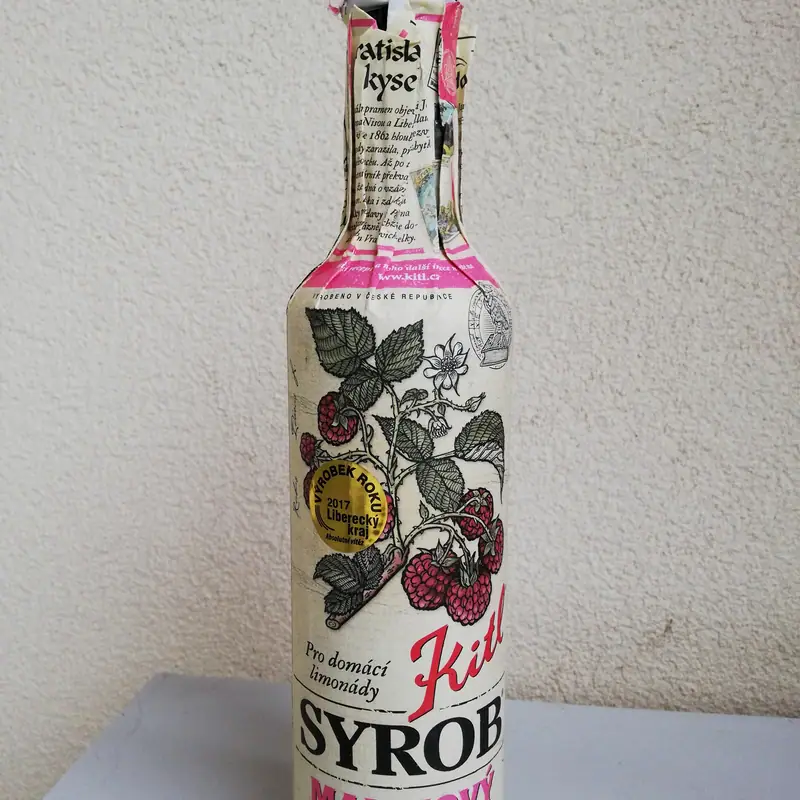 A bottle of raspberry syrup with pulp, labelled with raspberry illustrations
